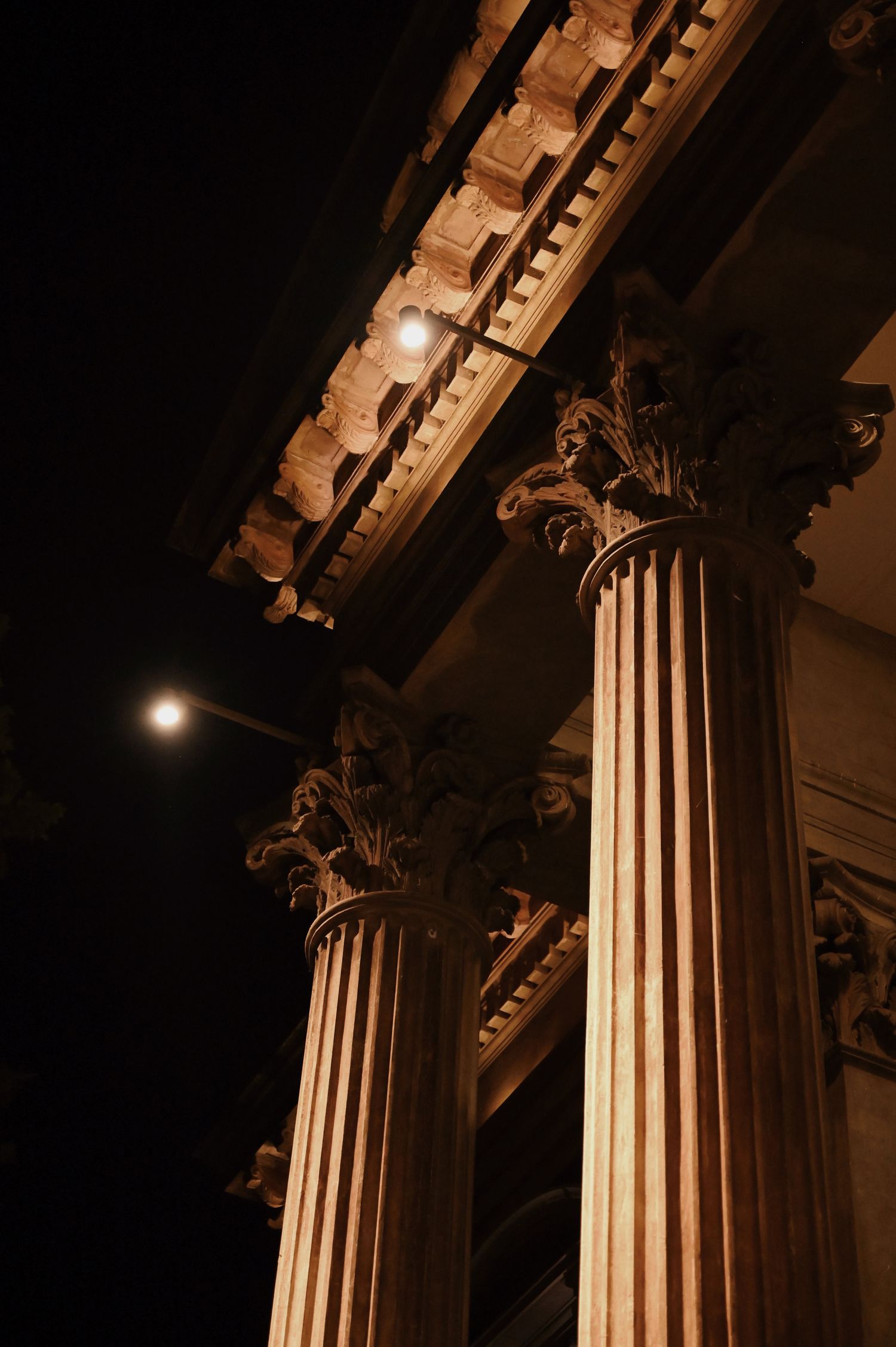 Illuminated classical stone columns against a night sky