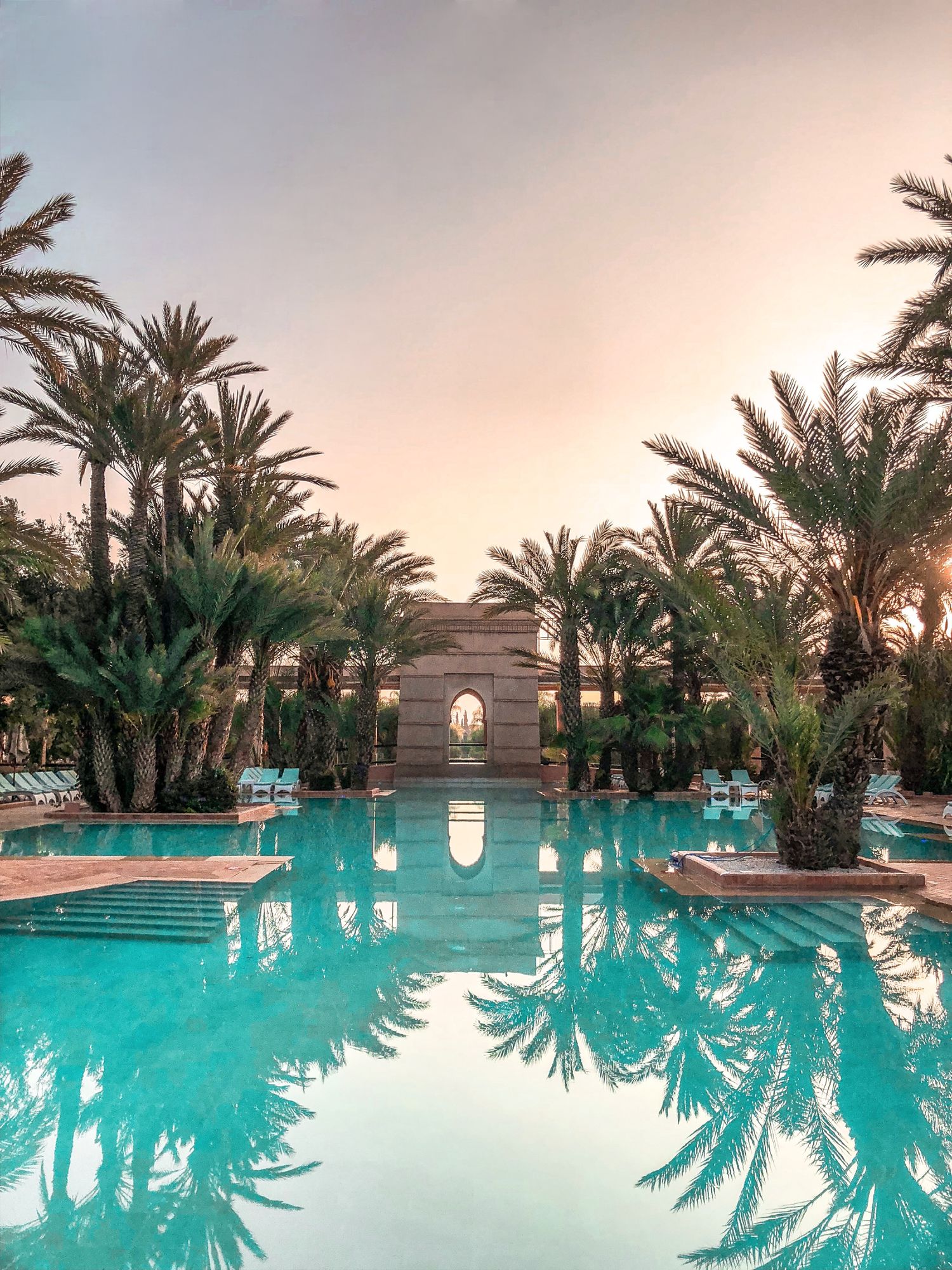 Illustrative leisure pool beneath palm trees at dusk